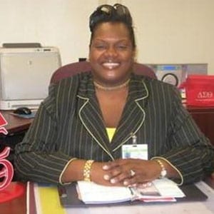 A woman sitting at her desk smiling for the camera.