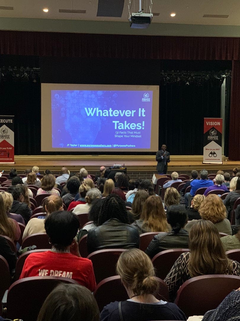 A large crowd of people in front of a screen.