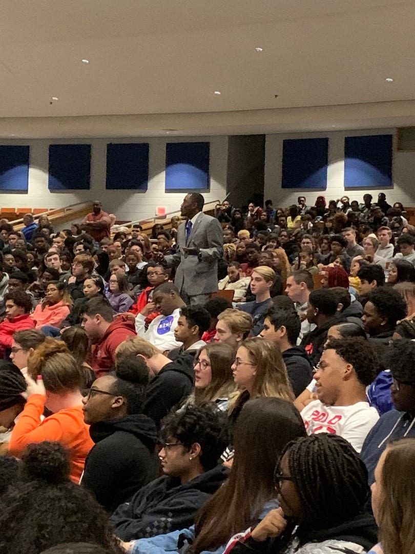 A large crowd of people sitting in front of a man.